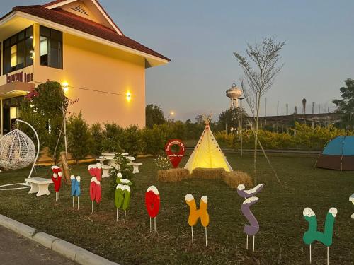 a garden with wooden figures of chickens and a tent at New blessing Home นิวเบลสซิ่ง โฮม in Nan