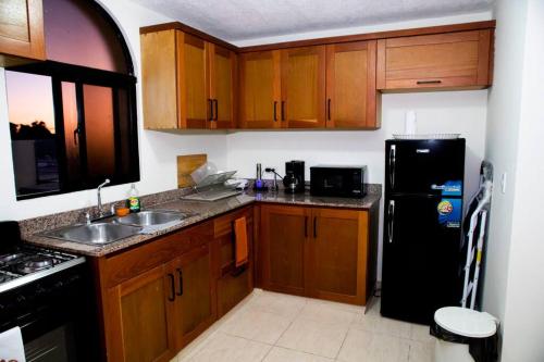 a kitchen with wooden cabinets and a black refrigerator at El más completo, a menos de 5 minutos de la playa, free wifi fuera del alojamiento in San Felipe de Puerto Plata