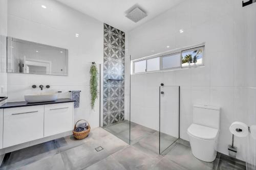 a white bathroom with a sink and a toilet at WhiteSands in Port Douglas