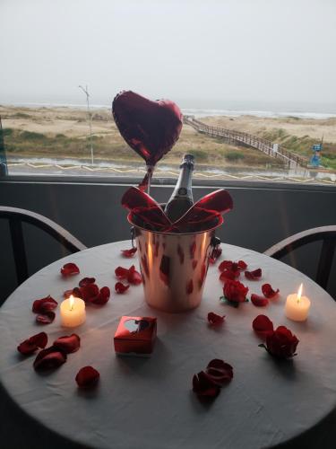 a table with roses and a bottle of champagne and candles at De Rose Praia Hotel in Torres