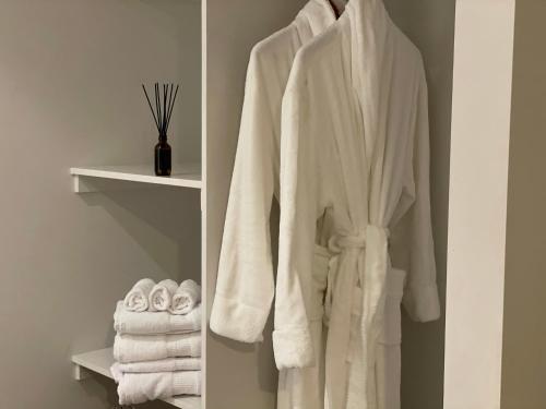 a white robe hanging on a rack in a bathroom at Cosy Cottage in the Vines in Waipara
