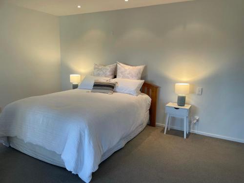a bedroom with a large white bed with two lamps at Cosy Cottage in the Vines in Waipara