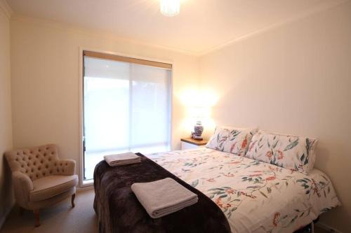 - une chambre avec un lit, une chaise et une fenêtre dans l'établissement Bridgecroft Cottage - Cosy 2 bedroom cottage, à Richmond
