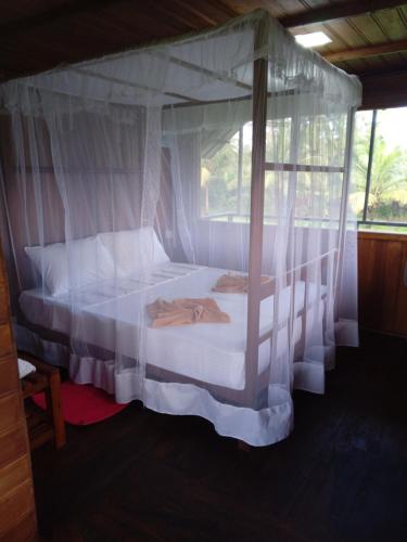 Un dormitorio con una cama con dosel y cortinas blancas. en Sigiriya Paddy Field Hut, en Sigiriya