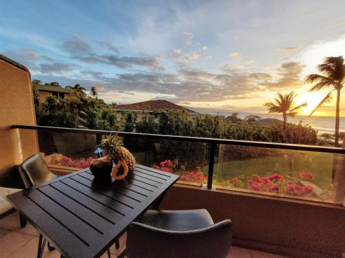 a table on a balcony with a view of the ocean at Hale Mai Hopohopo in Kahana