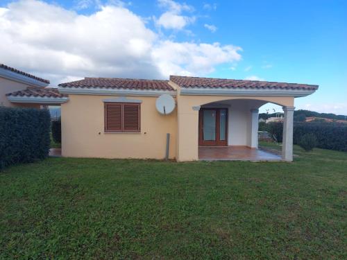a small yellow house with a green yard at Gallura Dream villas in Budoni