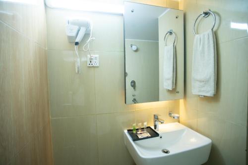 a bathroom with a sink and a mirror and a phone at Jatra Hotel Grand Royal in Dhaka