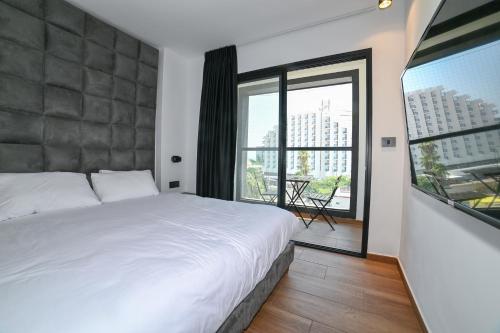 a bedroom with a white bed and a large window at Selfie's Boutique Hotel in Tiberias
