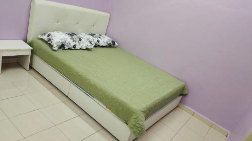 een slaapkamer met een bed met een groen dekbed bij Muslim Dinaim Homestay in Tanjung Malim