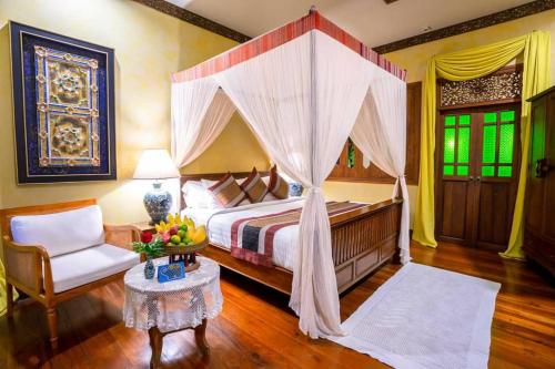 a bedroom with a canopy bed and a chair and a table at Amata Lanna Village อมตะล้านนาวิลเลจ in Chiang Mai