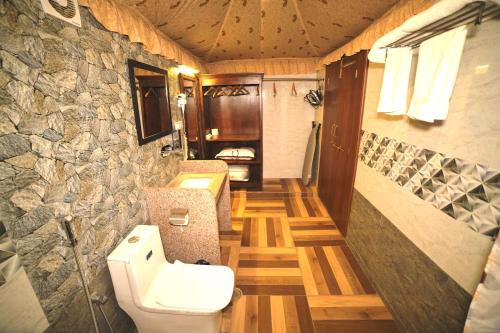 a bathroom with a toilet and a stone wall at Amrit Van Resort in Jaipur