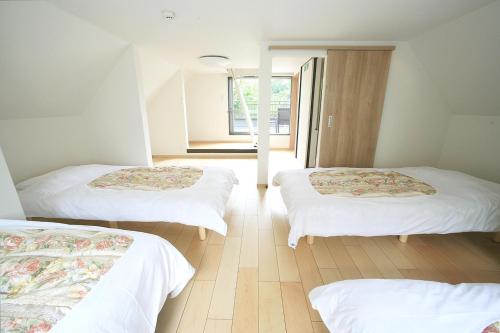 pokój z 3 łóżkami i białą pościelą w obiekcie Y's あたみんち w mieście Atami