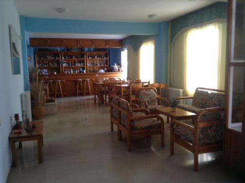 a living room with chairs and tables and a bar at Haritos Hotel - Geothermal Hot Swimming Pool in Mandrakion