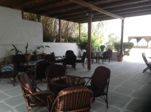 an outdoor patio with tables and chairs and tablesearcher at Haritos Hotel - Geothermal Hot Swimming Pool in Mandrakion