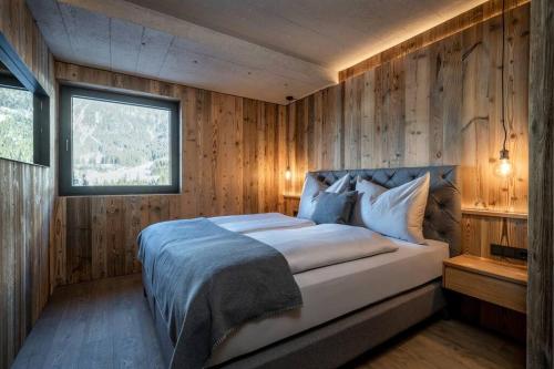 1 dormitorio con 1 cama grande y paredes de madera en STADEL CHALET, en Annaberg im Lammertal