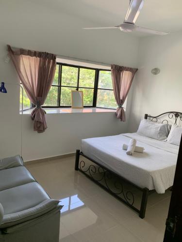 a bedroom with a bed and a chair and windows at 3 bedroom Paul Meranti A303 Genting Highland Vacation Home in Genting Highlands