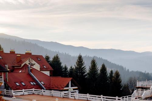 a building with a red roof with mountains in the background at Wellland Hotel in Yaremche