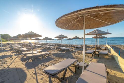 a beach with chairs and umbrellas and the ocean at Atik Hotel in Unye
