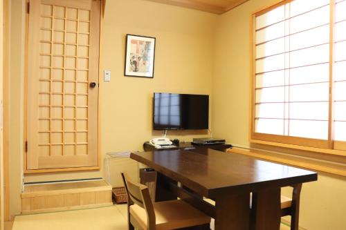 a dining room with a table and a television at Ryokan Kamogawa Asakusa in Tokyo