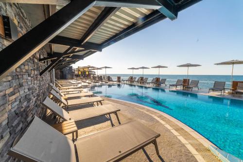 a swimming pool with lounge chairs and the ocean at Atik Hotel in Unye