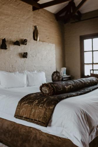 a bedroom with a large bed with a leather seat at African Leaves Trout Lodge in Dullstroom