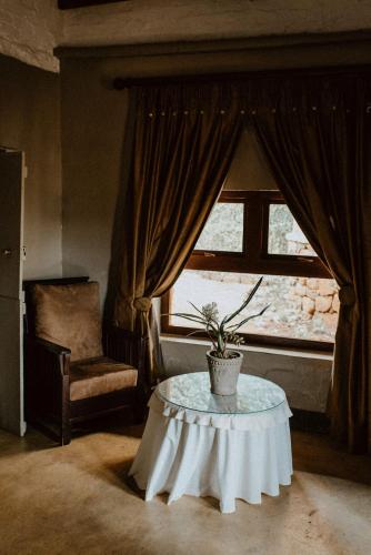 a living room with a table and a window at African Leaves Trout Lodge in Dullstroom