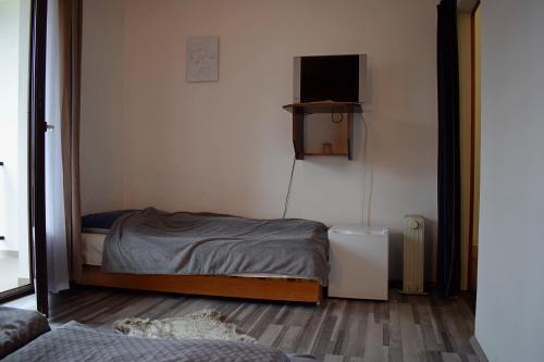a small bedroom with a bed and a tv on the wall at Két Diófa Vendégház in Felsőtárkány