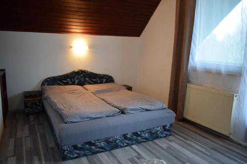 a small bed in a room with a window at Két Diófa Vendégház in Felsőtárkány