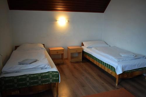 two beds in a room with two night stands at Két Diófa Vendégház in Felsőtárkány