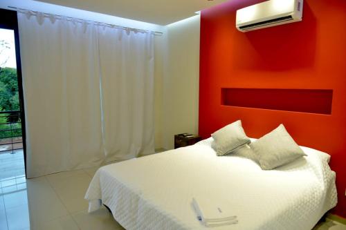 a bedroom with a white bed with an orange wall at Tekoa Lodge in Puerto Iguazú