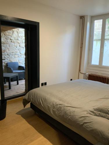 1 dormitorio con cama, silla y espejo en Le charme de l'ancien, en Bourges