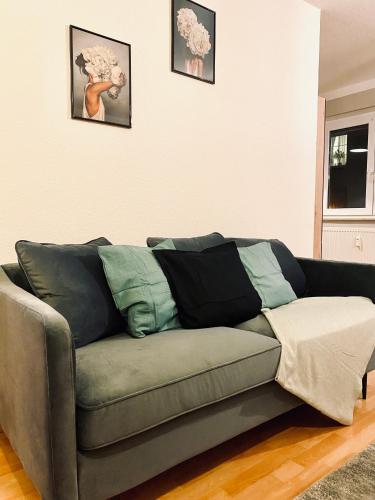 a couch in a living room with two pictures on the wall at Saniertes Studio - Elisa - mit Balkon, WLAN, Smart-TV & Küche in City-Nähe in Erfurt