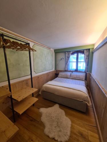 1 dormitorio con cama, ventana y alfombra en Bilocale Ristrutturato, en Madesimo