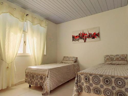 a bedroom with two beds and a window at Casa Petit - Banheiro Exclusivo in Natal