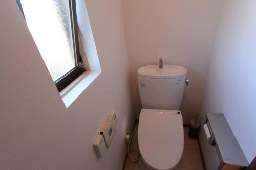 a bathroom with a white toilet and a window at 2022年NO.1ビーチもまるごと貸切冬OK屋根付暖房/BBQ場完備/カラオケ/キャンプファイヤー in Chōjamachi