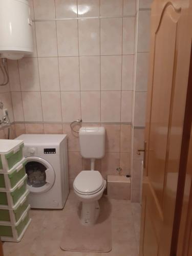 a small bathroom with a toilet and a washing machine at Apartman Neda in Kupres