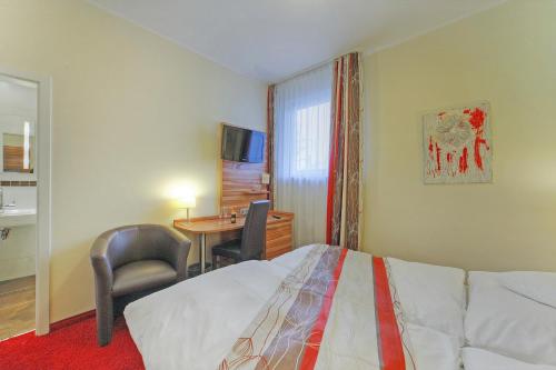 a hotel room with a bed and a desk and chair at Hotel Da Vinci in Gröbenzell