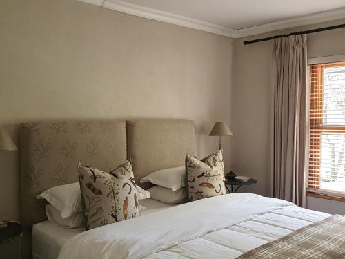 una camera da letto con letto, lenzuola e cuscini bianchi di Shepherd's Cottage a Nieu-Bethesda
