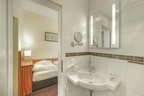 a bathroom with a sink and a bed at Hotel Da Vinci in Gröbenzell