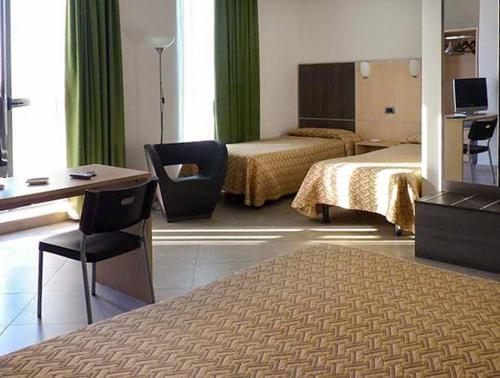Pokój hotelowy z 2 łóżkami, biurkiem i krzesłem w obiekcie Hotel Lux w mieście Modena