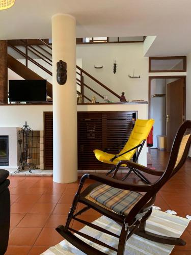 a yellow chair in a living room with a fireplace at Moradia próxima da praia do Areinho, na Ria, e praia dos Marretas in Ovar
