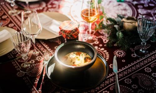 a table with a bowl of food on a table with wine glasses at Ati Ambavi Botique Hotel Gudauri in Gudauri