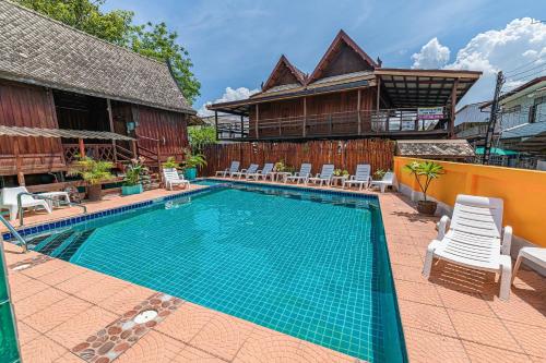 a swimming pool with chairs and a house at MANDARIN LODGE by victor in Hua Hin