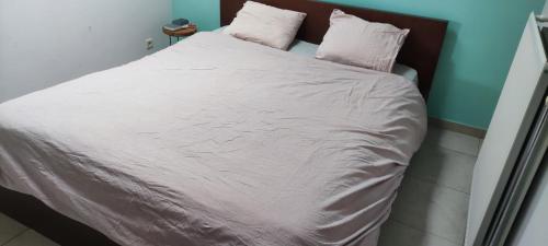 a bed with white sheets and pink pillows on it at loft appartement met 3 slaapkamers en gratis parking in Ichtegem
