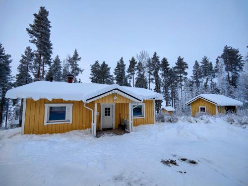 two wooden cabins with snow on the roofs at Lake Cottage Jänisvaara in Kolinkylä