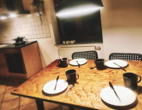 uma mesa de madeira com pratos e utensílios em Apartment DOMO Kirchzarten em Kirchzarten