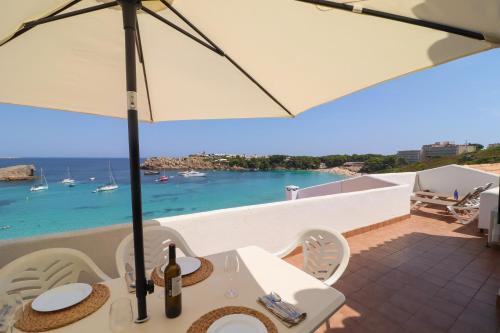 a table with an umbrella and a view of the ocean at Belvedere, Family-friendly, Nice, First-line Apartment with Stunning Beach and Sea views,AC in Arenal d'en Castell