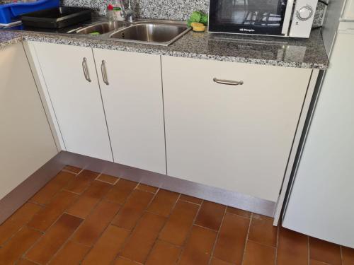 a kitchen with white cabinets and a sink at Belvedere, Family-friendly, Nice, First-line Apartment with Stunning Beach and Sea views,AC in Arenal d'en Castell