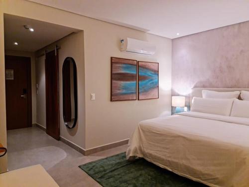 a bedroom with a large bed and a painting on the wall at Flat Deluxe no centro de Pipa in Pipa