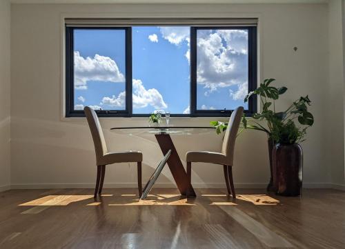 a dining room table and two chairs in front of a window at The Botanical 304 in Albury